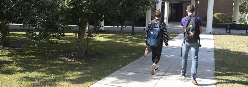 A picture of two students walking on campus on a beautiful summer day.
